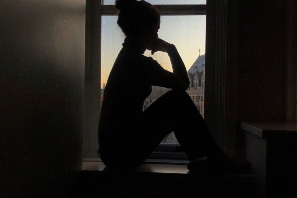 Silhouette of a woman sitting alone, reflecting in a window.