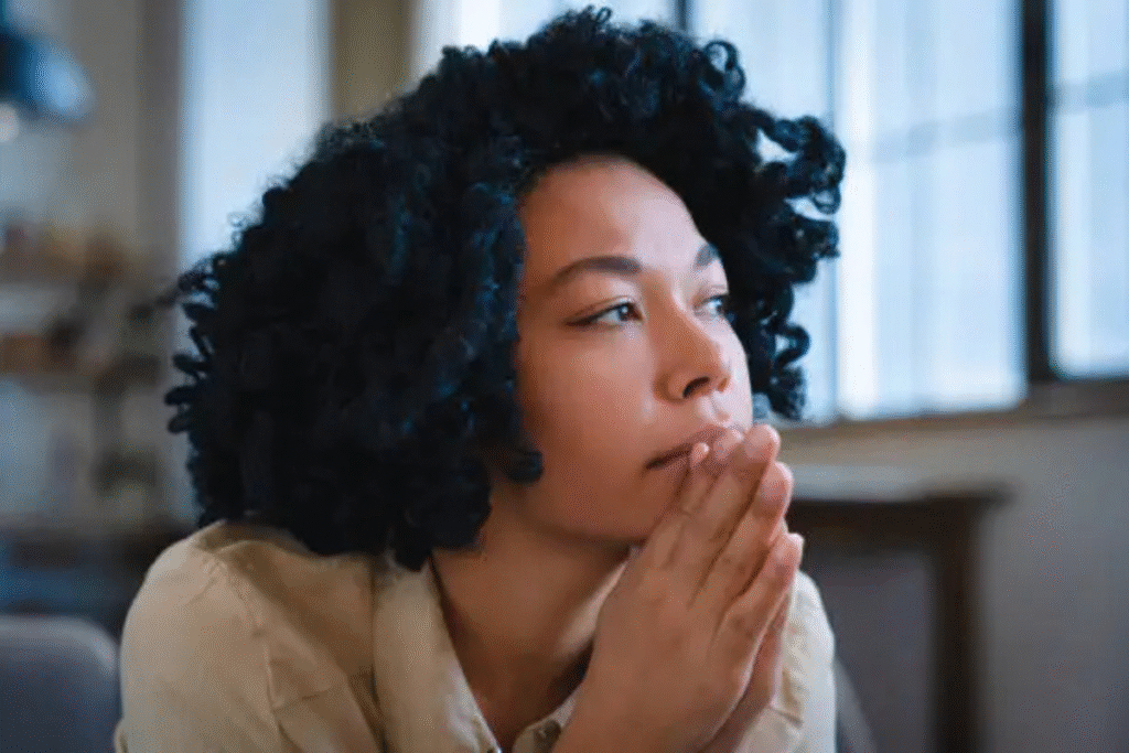 Woman sitting with her hands together, looking deep in thought and reflecting.